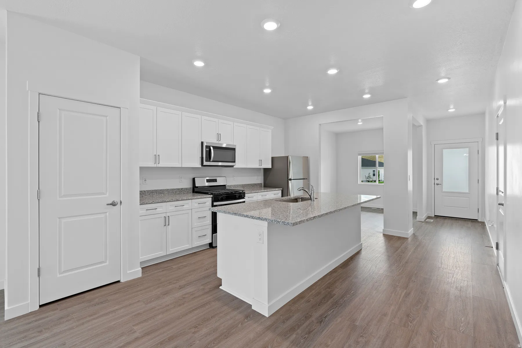 Kitchen featuring white cabinets, stainless steel appliances, a kitchen island with sink, dark wood finished floors, and recessed lighting