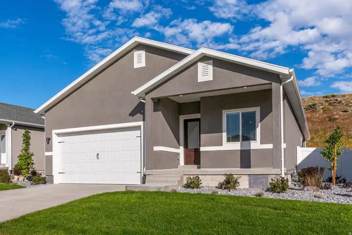 View of front facade featuring stucco siding, driveway, an attached garage, and covered porch