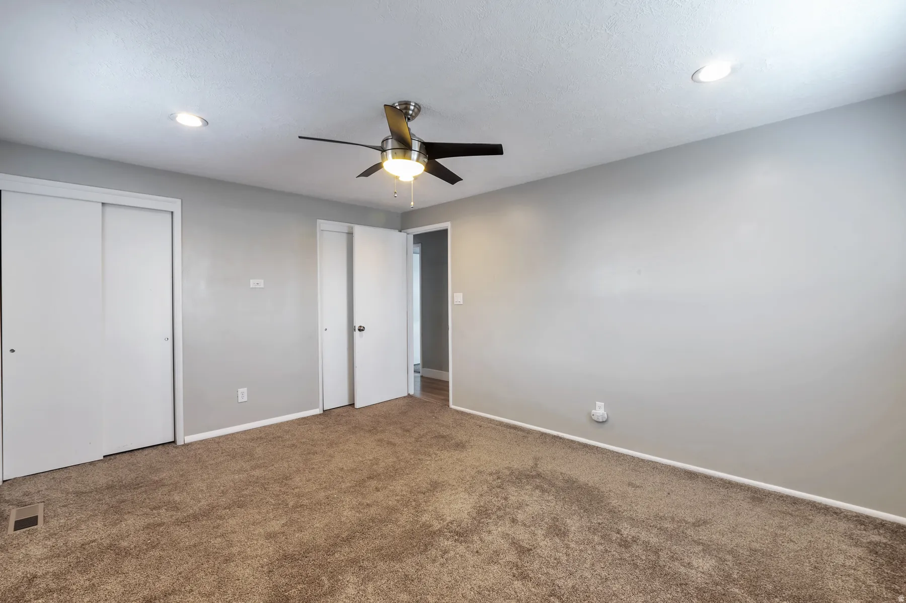Unfurnished bedroom featuring two closets, carpet flooring, ceiling fan, and recessed lighting
