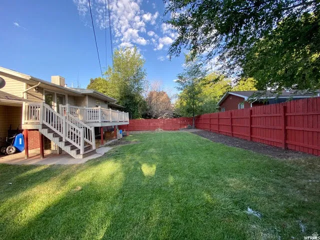 Fenced backyard featuring a wooden deck and a patio