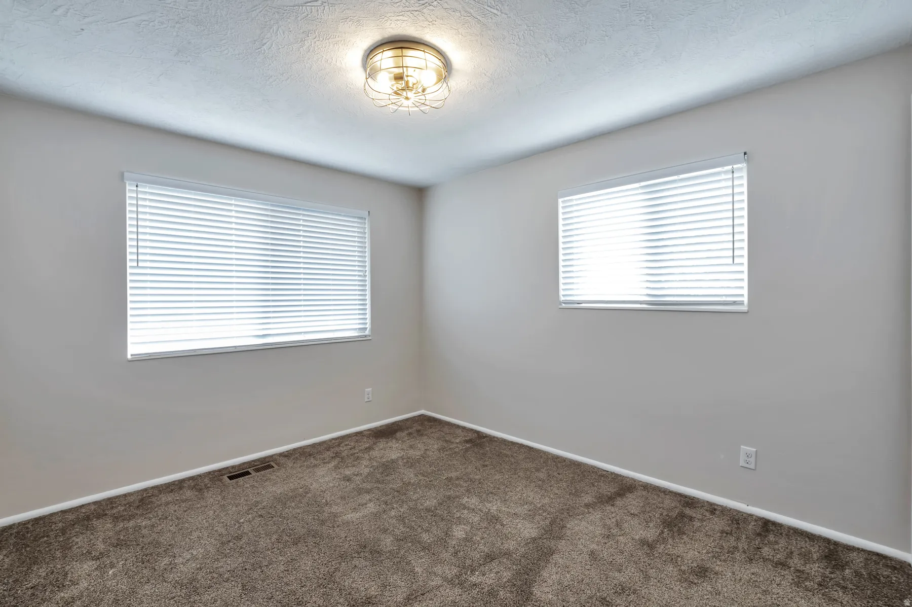 Empty room featuring dark carpet and a textured ceiling