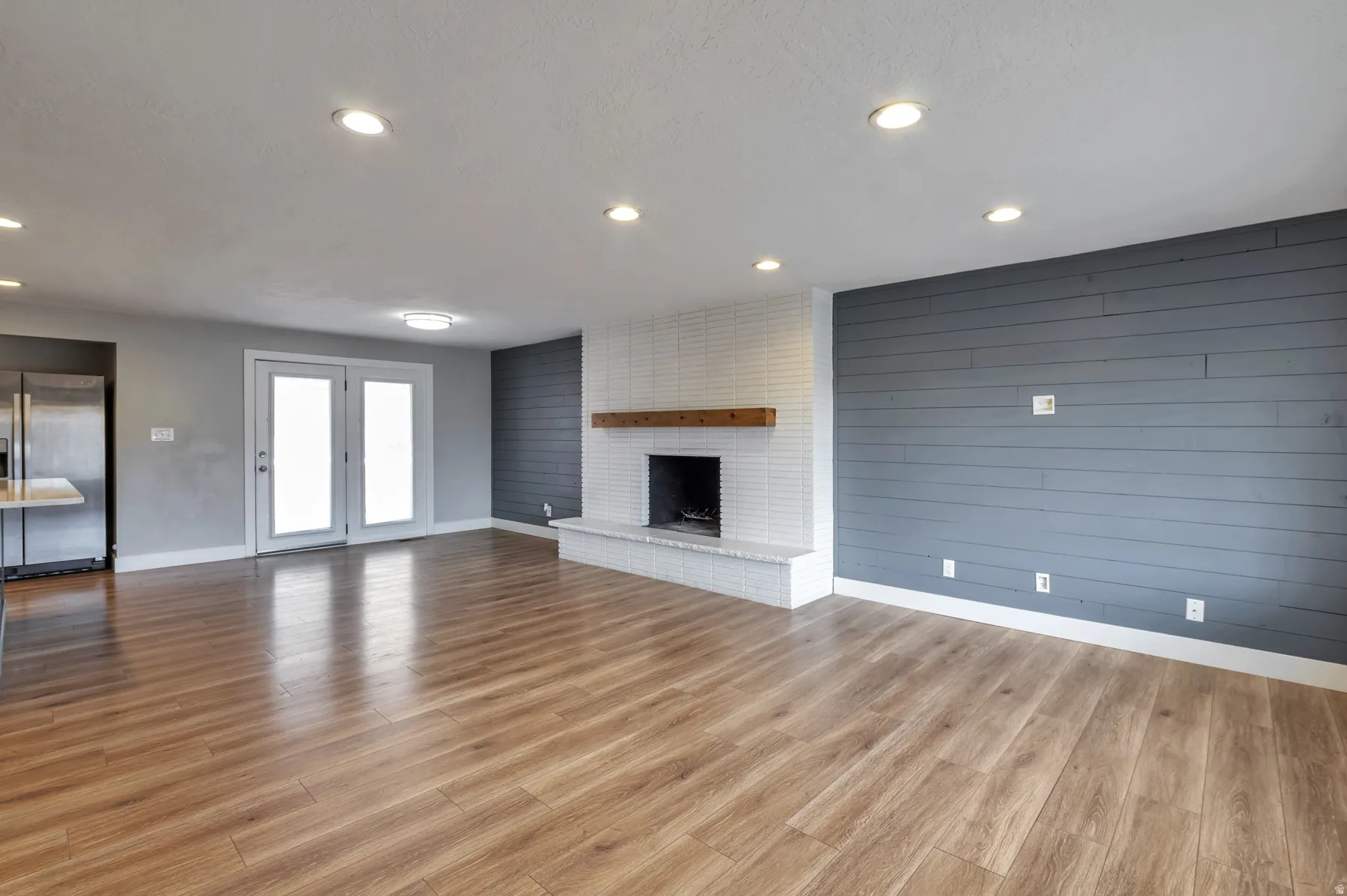 Unfurnished living room with wood walls, light wood finished floors, a fireplace, and recessed lighting