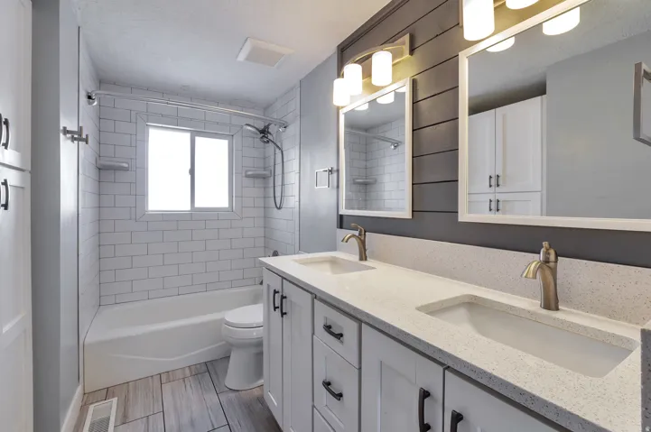 Bathroom with double vanity, shower / tub combination, and wood tiled floors