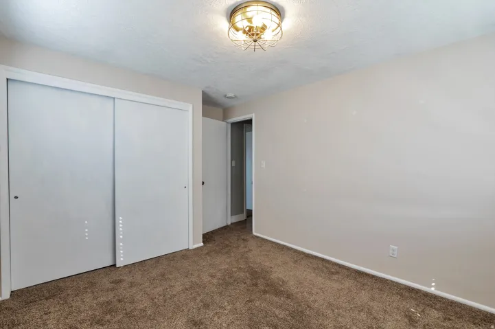 Unfurnished bedroom featuring a closet, dark colored carpet, and a textured ceiling