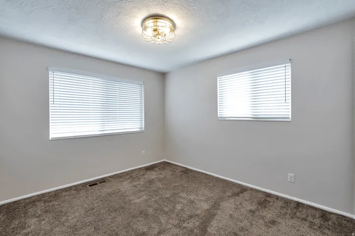 Empty room featuring dark carpet and a textured ceiling