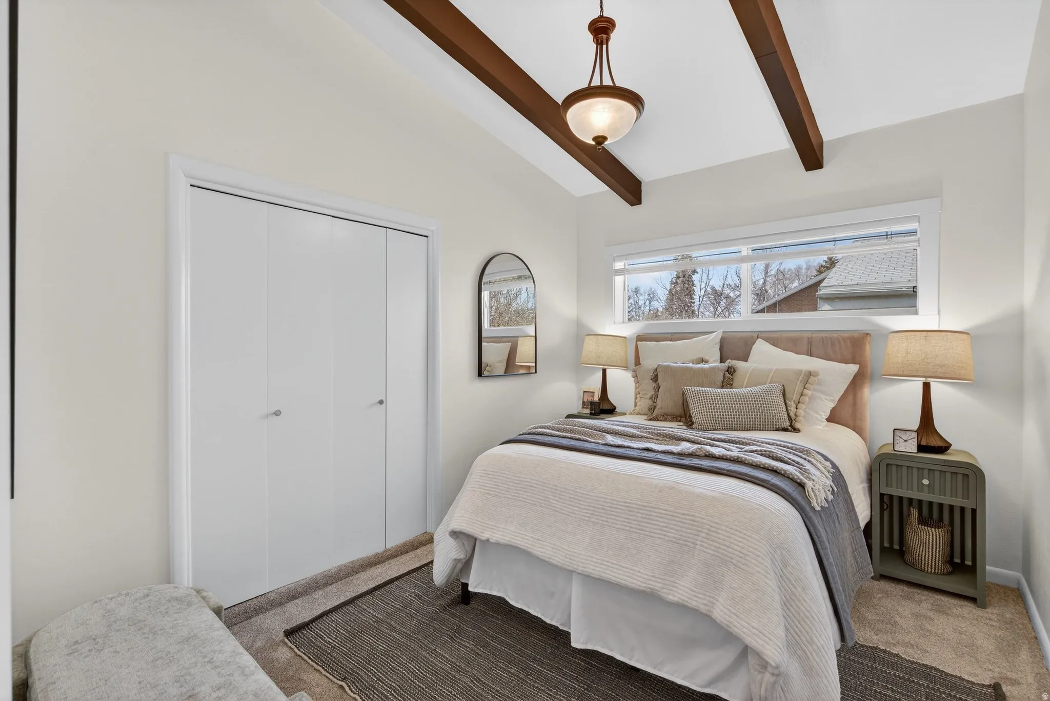 Bedroom #4 featuring vaulted ceiling with beams, soft neutral carpeting and a chandelier. This bright bedroom is designed for rest and relaxation.