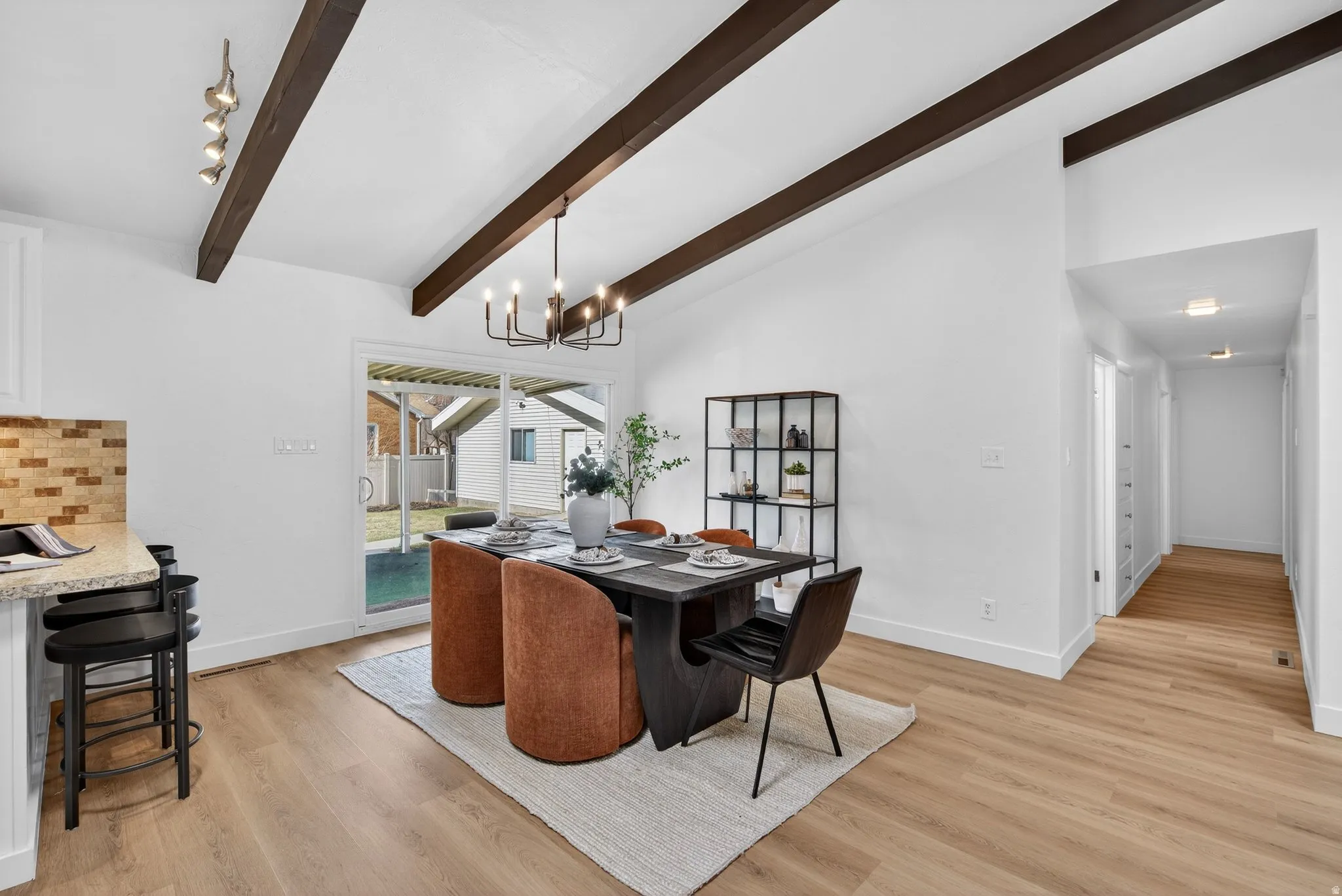 Dining space featuring soaring vaulted ceilings and rustic beams that create an open, airy feel. A suspended chandelier provides elegant lighting while light-toned flooring keeps the aesthetic fresh and modern.