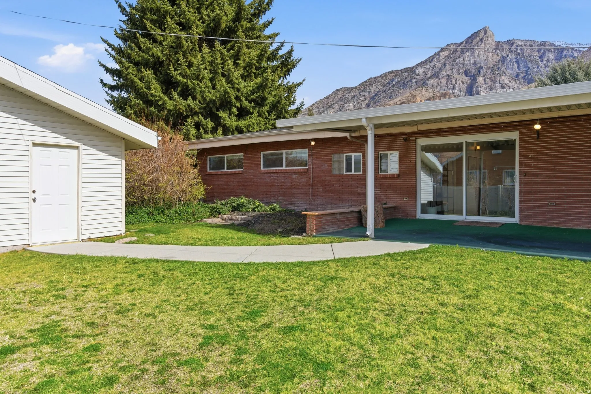 Spacious backyard featuring a classic brick facade and an oversized patio.