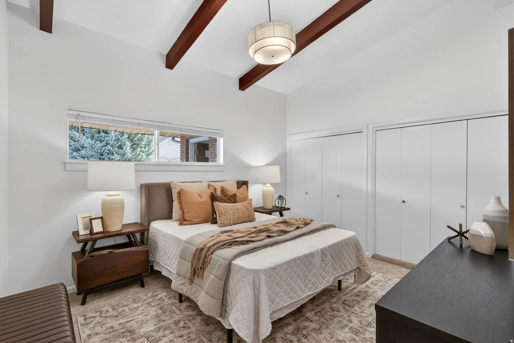 Primary Bedroom featuring vaulted ceiling with beams and an elegant statement chandelier. Complete with soft neutral carpeting, this bright and spacious bedroom is designed for relaxation.