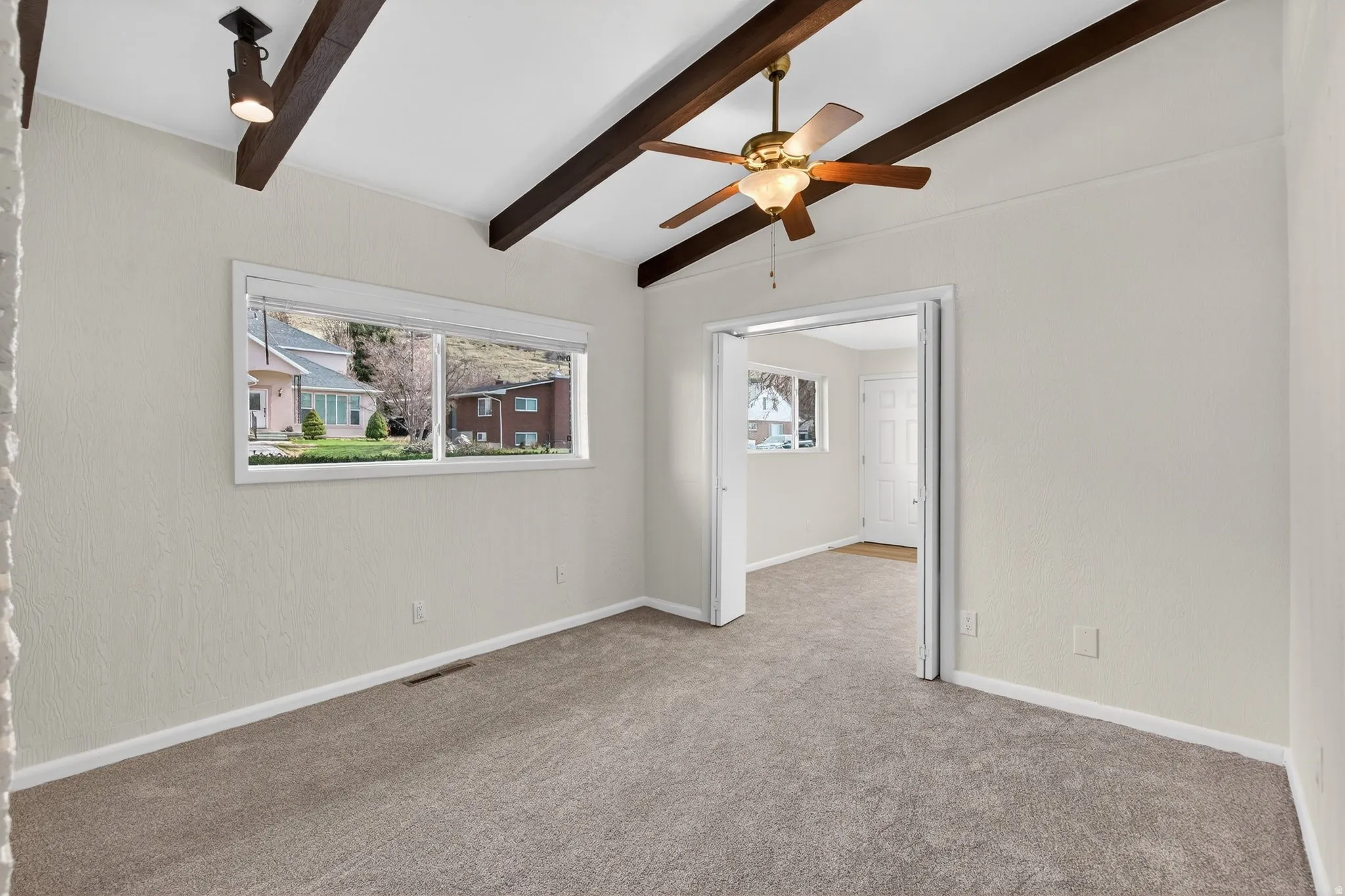 Flex-room featuring lofted beamed ceilings and a stately brick fireplace. Would make a great home office or music room with neutral carpeting, natural light and character.