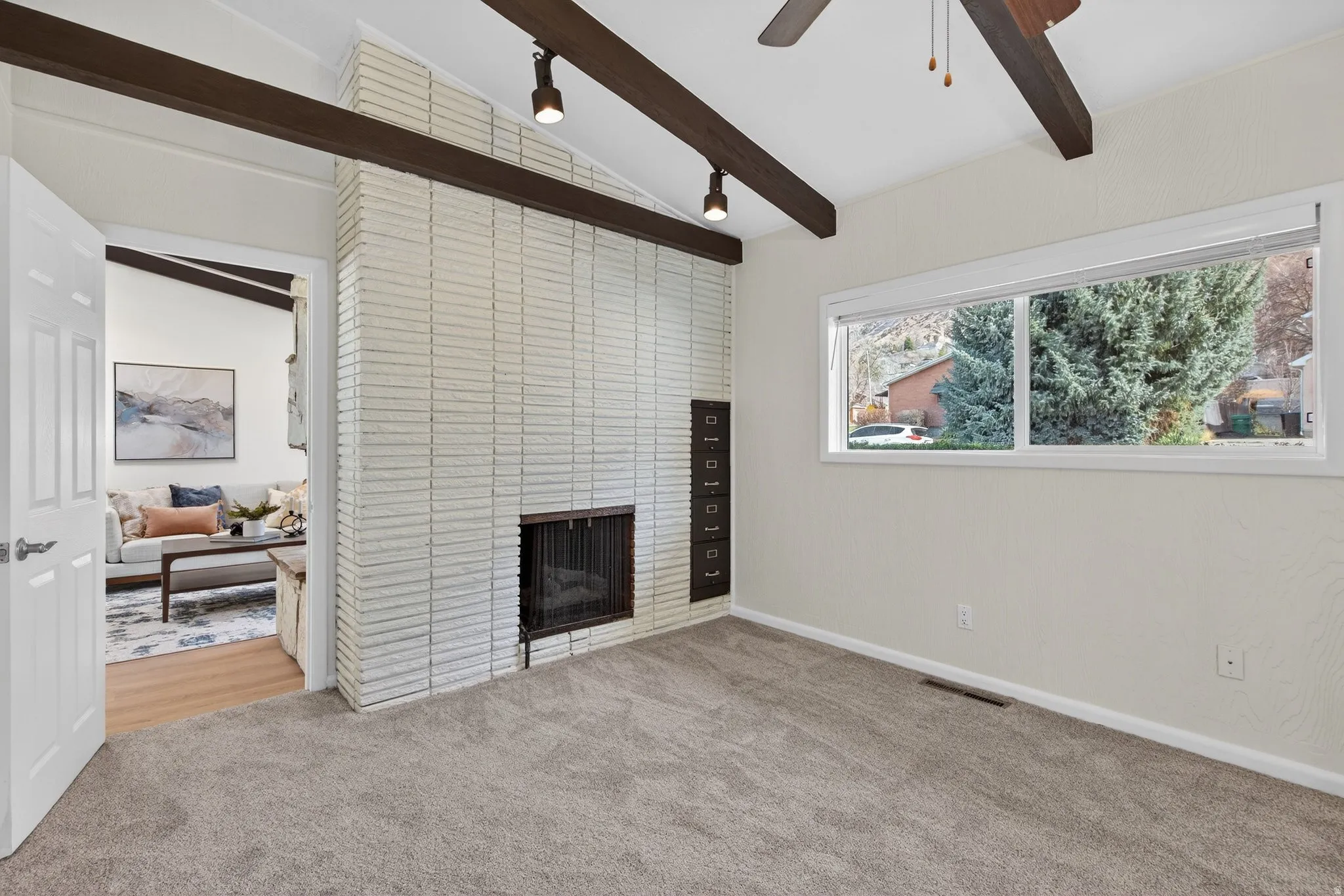 Flex-room featuring lofted beamed ceilings and a stately brick fireplace. Would make a great home office or music room with neutral carpeting, natural light and character.