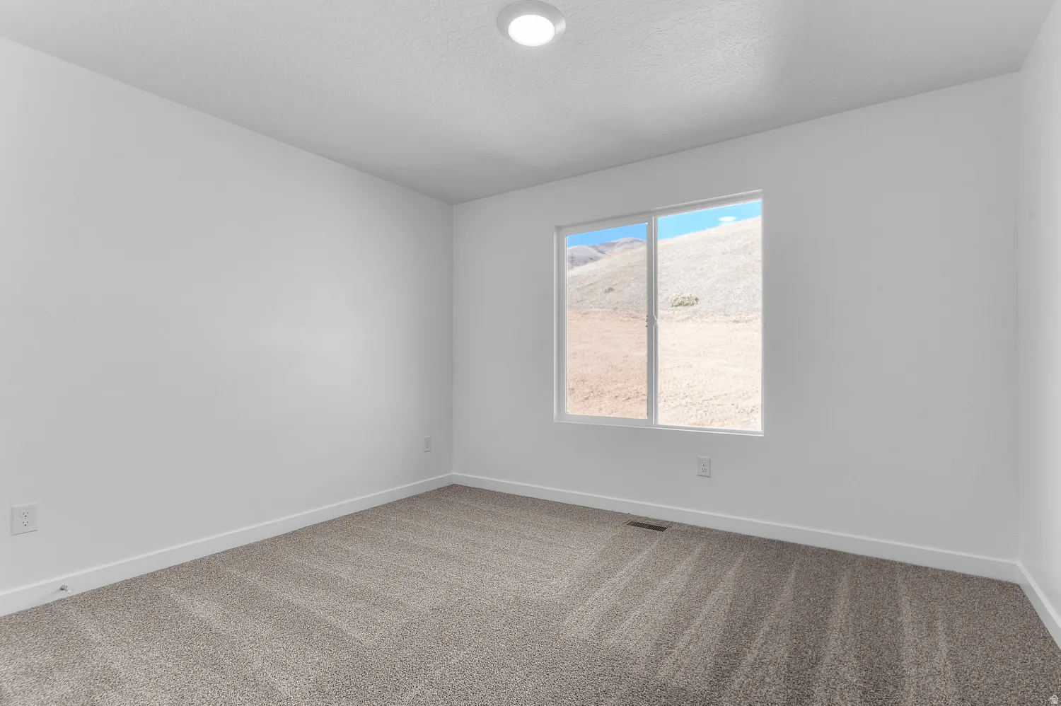 Carpeted empty room with baseboards and a textured ceiling