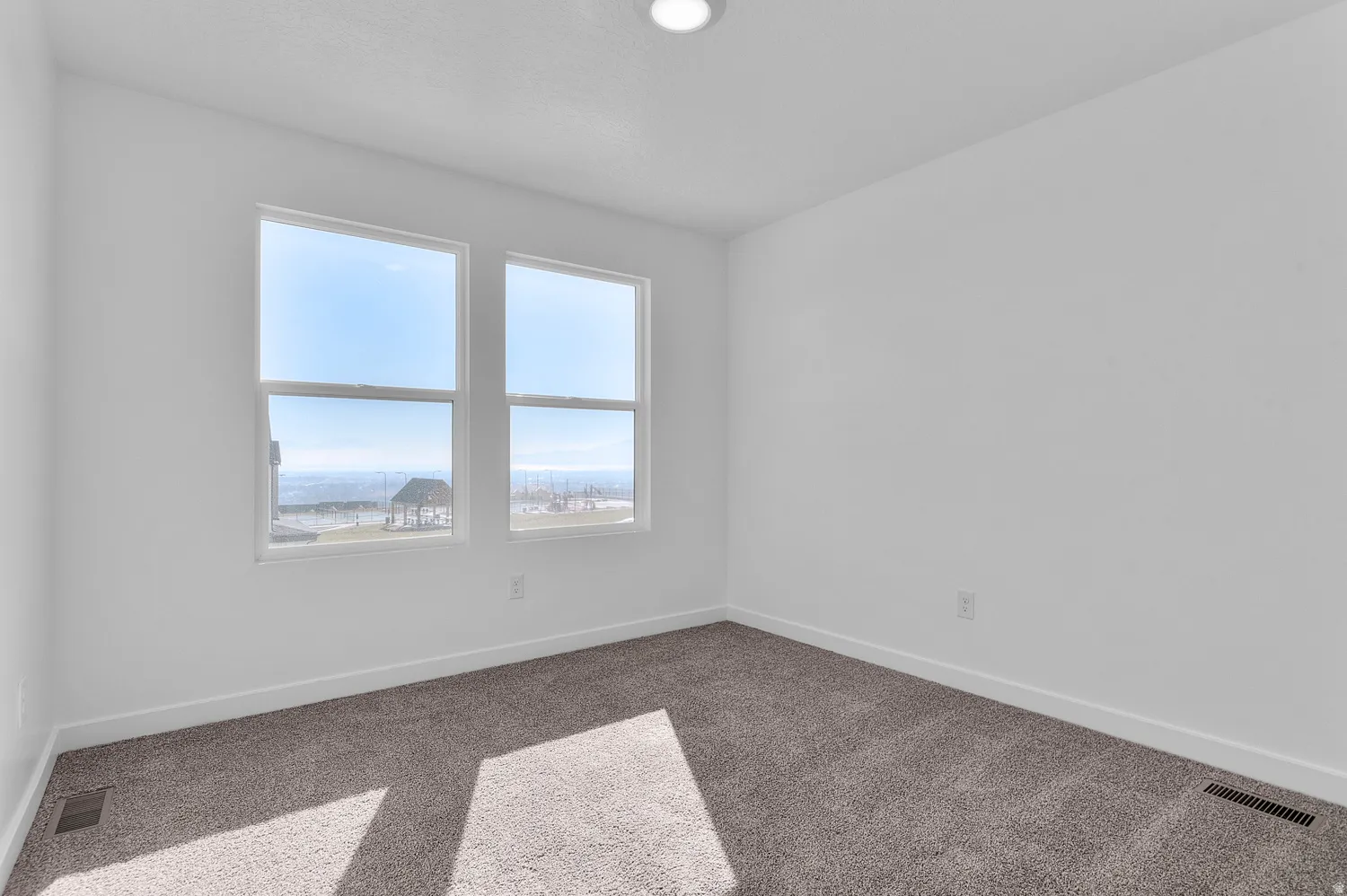 Carpeted spare room featuring baseboards