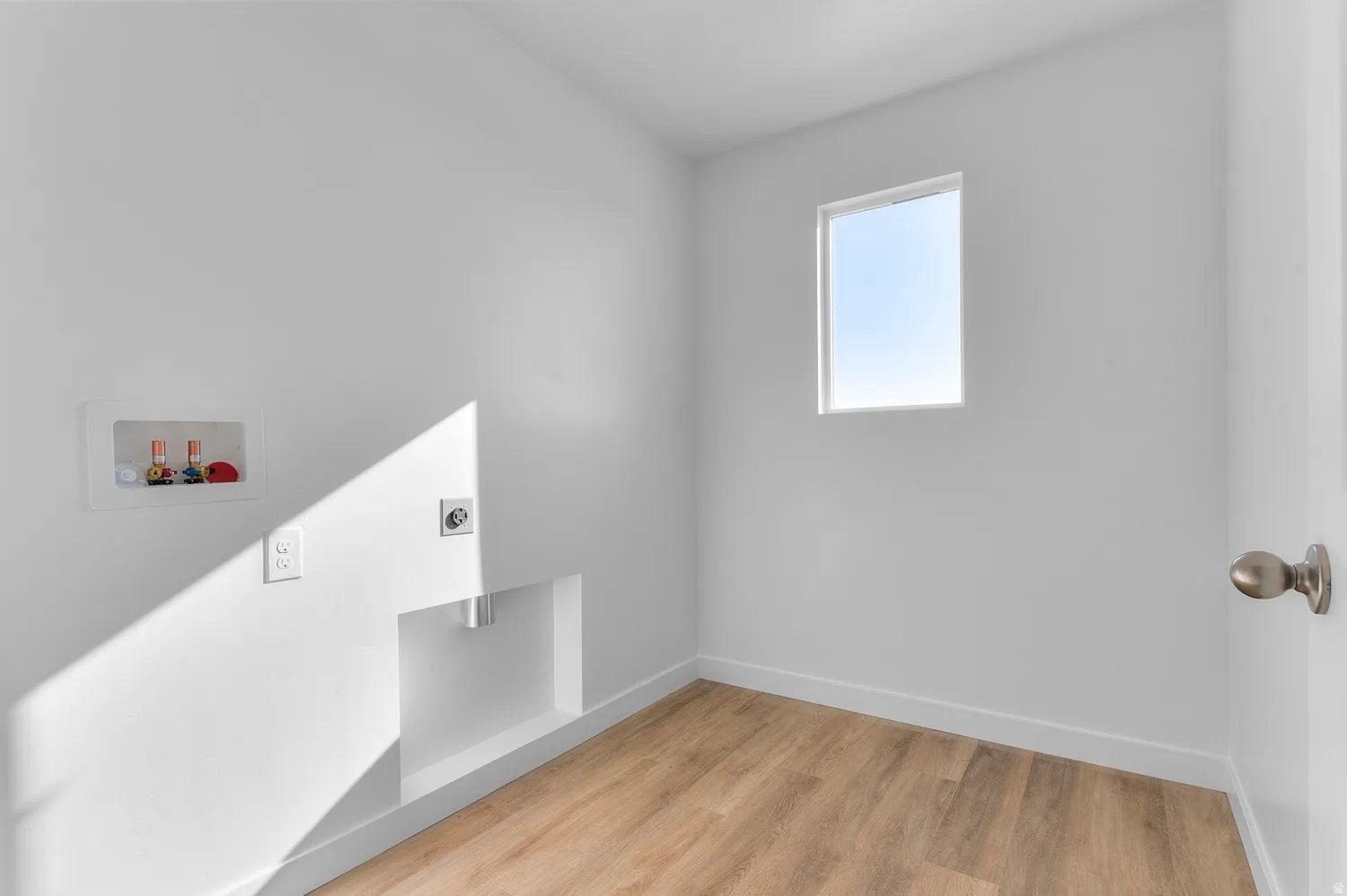 Laundry area with light wood-style flooring, washer hookup, and hookup for an electric dryer