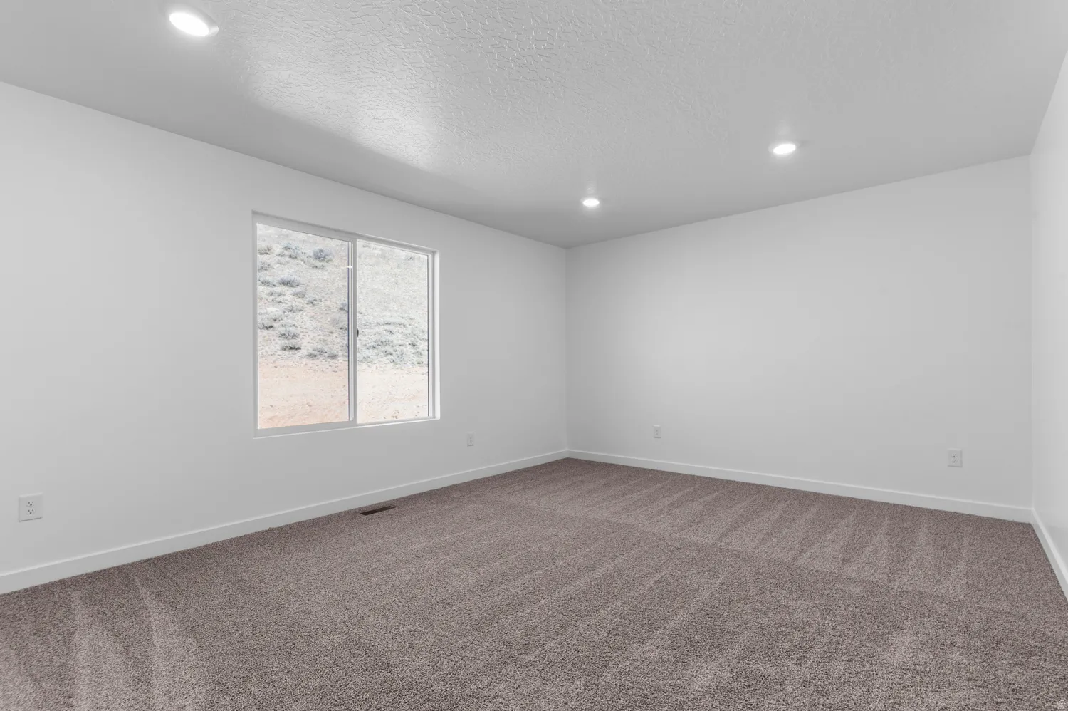 Empty room with dark colored carpet, recessed lighting, and a textured ceiling
