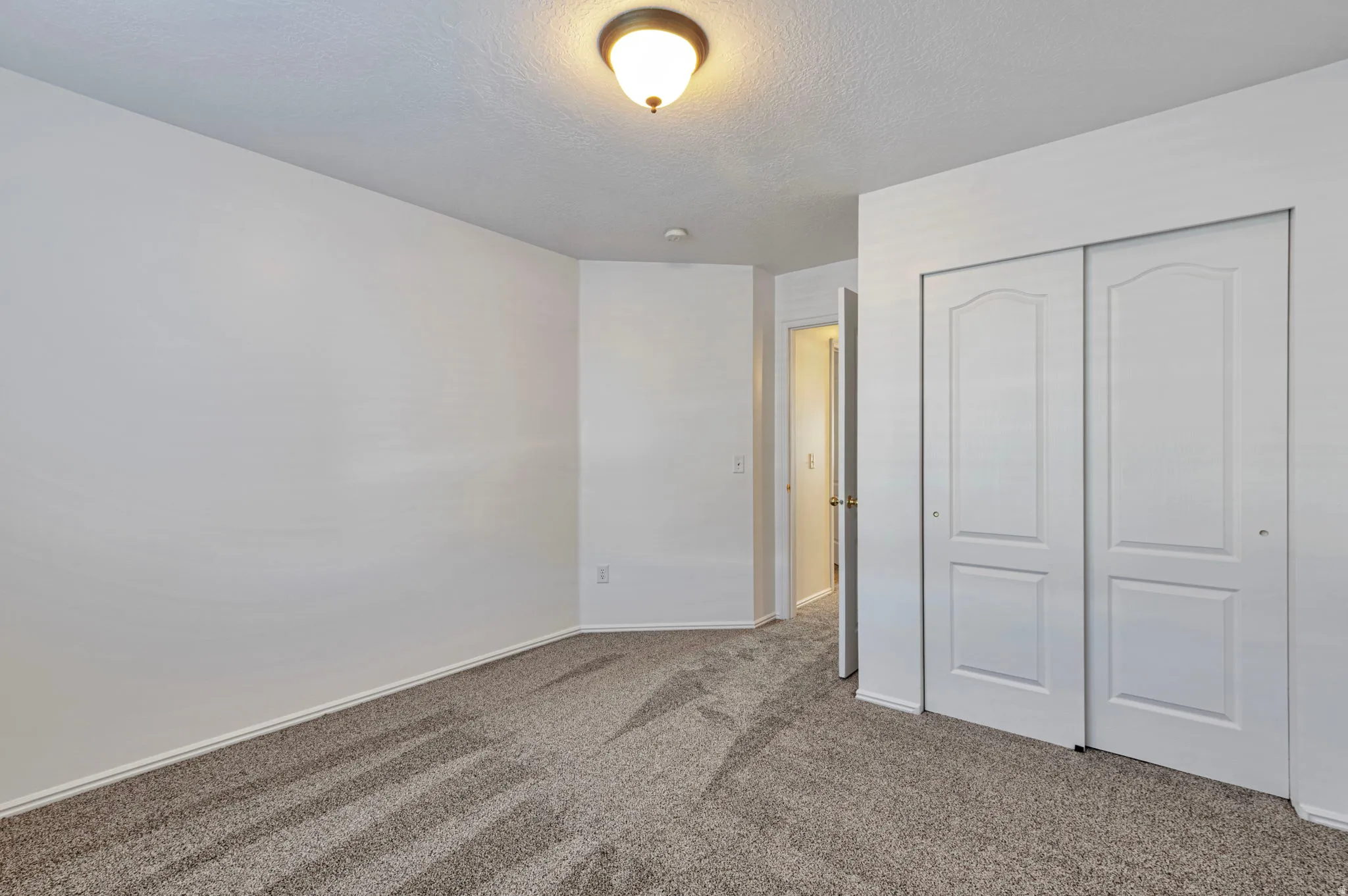 Unfurnished bedroom with carpet flooring, a closet, and a textured ceiling