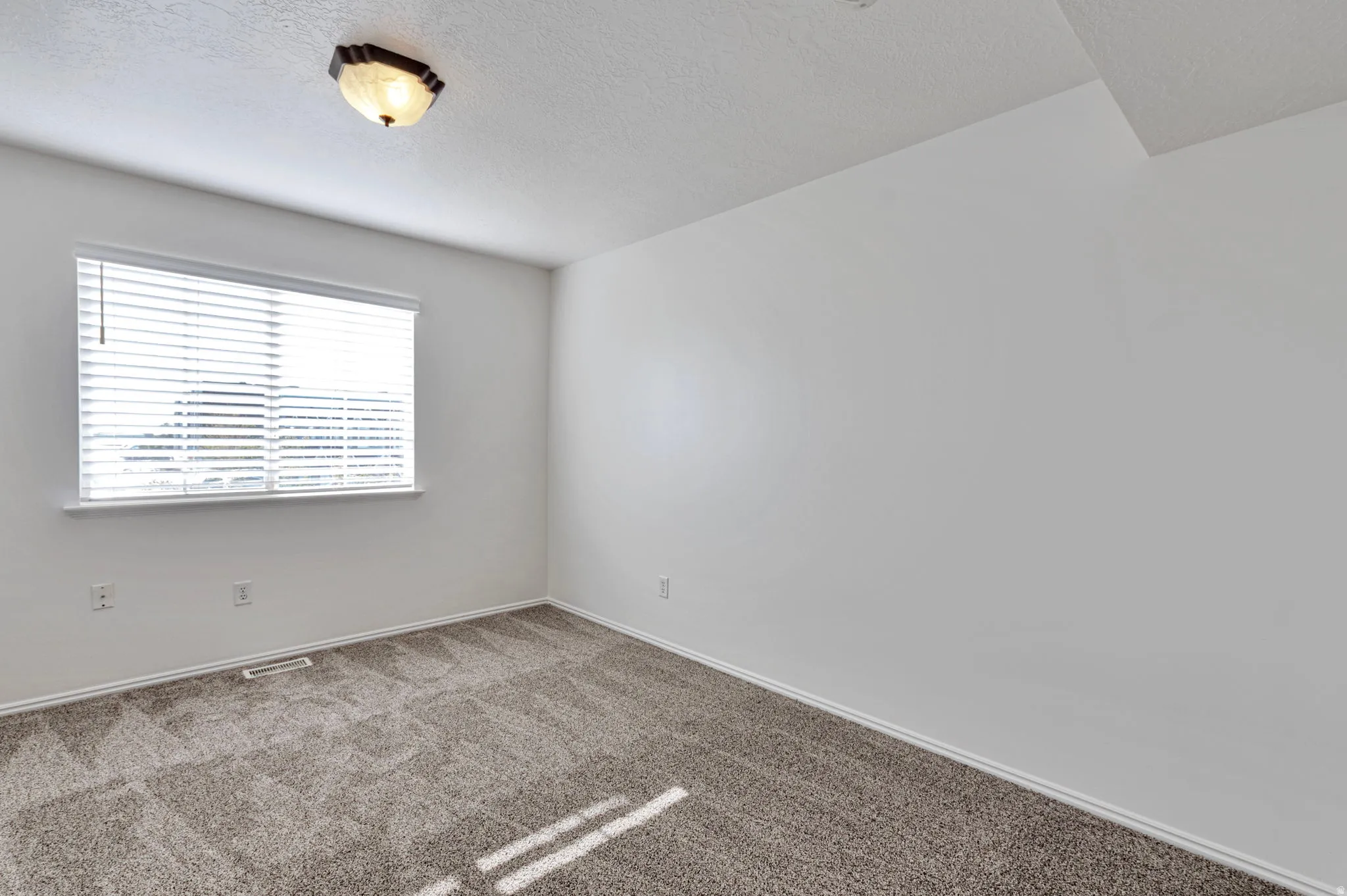 Carpeted empty room featuring a textured ceiling and baseboards