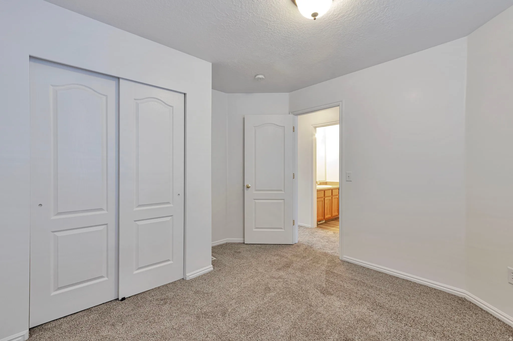 Unfurnished bedroom featuring light carpet, a closet, and a textured ceiling