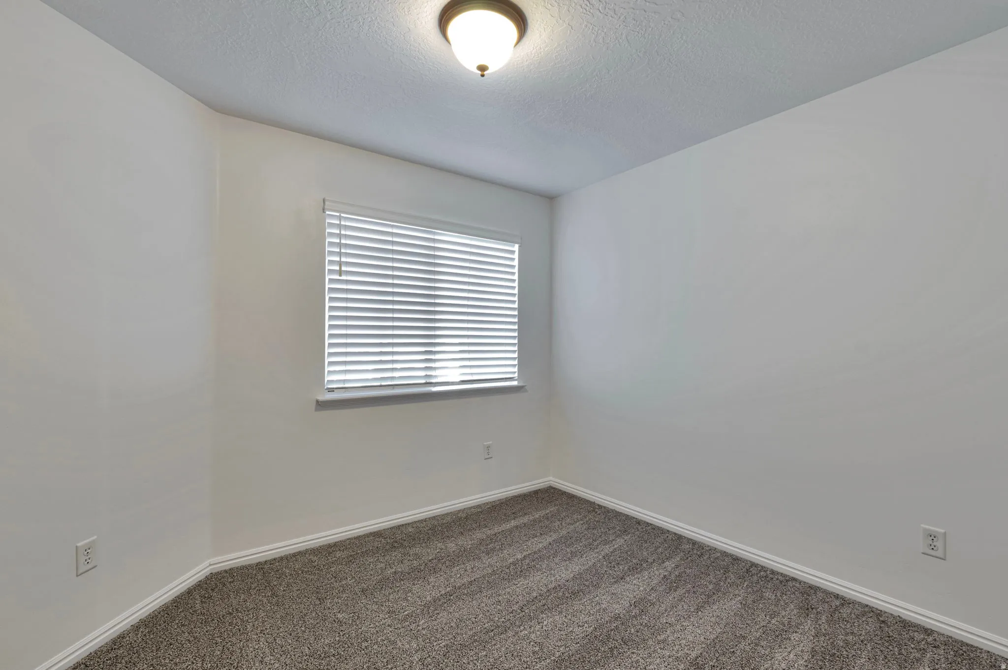 Spare room featuring dark colored carpet and a textured ceiling