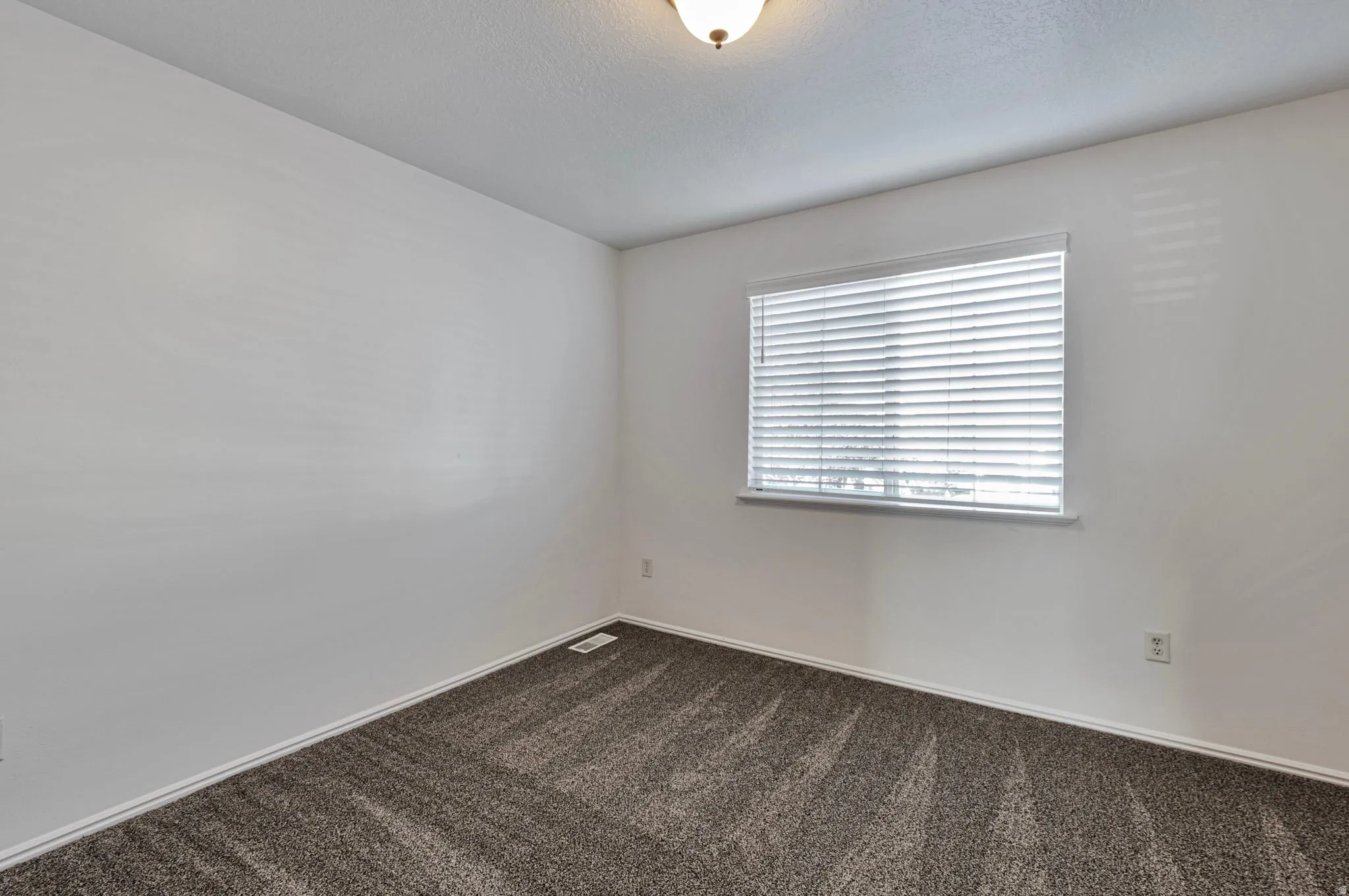 Spare room featuring dark colored carpet and a textured ceiling