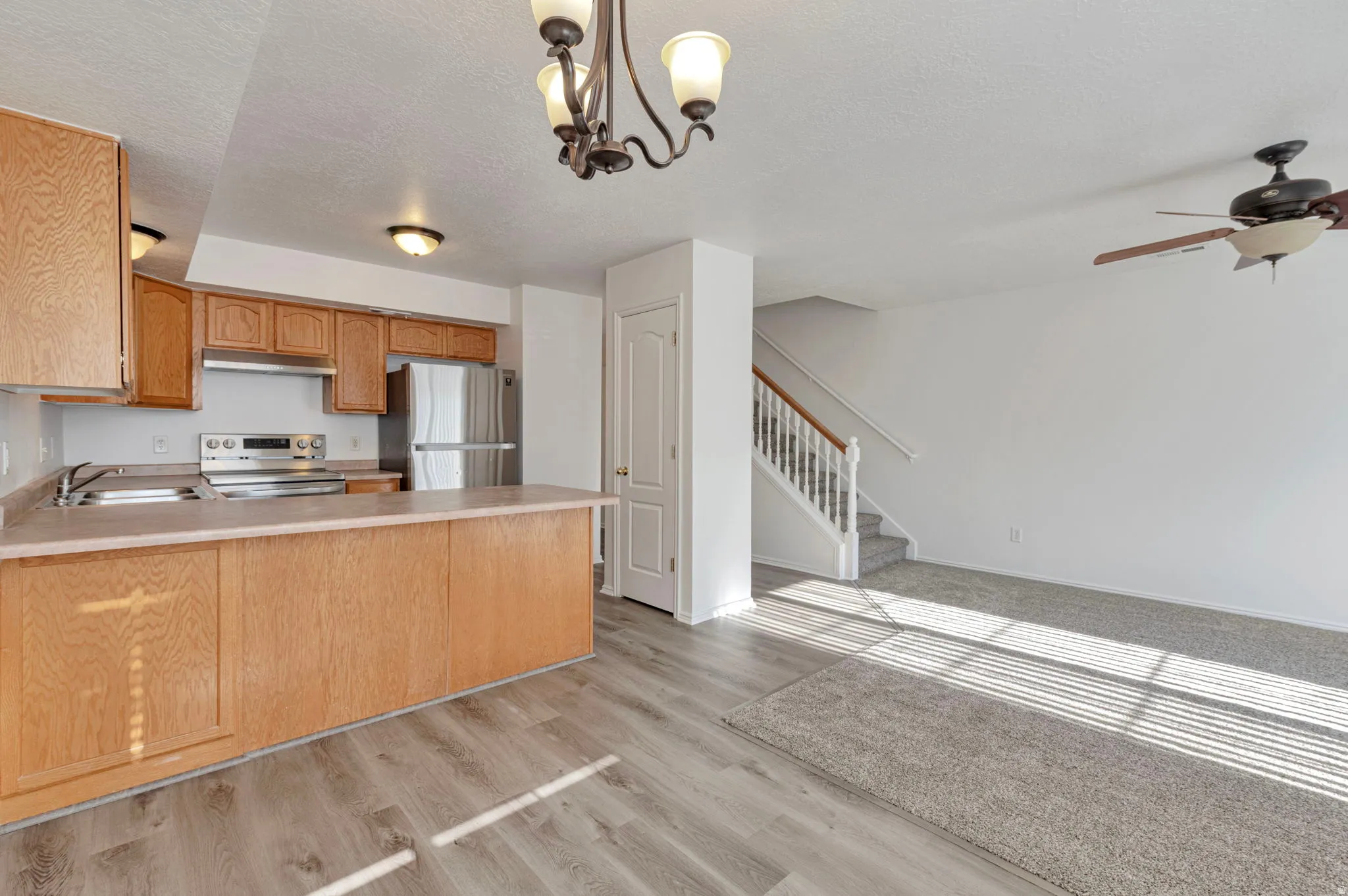Kitchen featuring light countertops, stainless steel appliances, a peninsula, hanging lights, and a textured ceiling