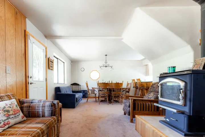 Living area with light colored carpet, suspended lighting, and beam ceiling