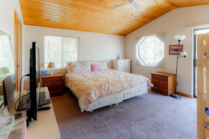 Carpeted bedroom featuring a vaulted wood ceiling and a ceiling fan