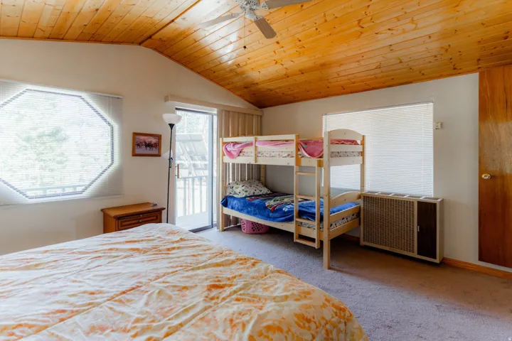 Bedroom with a vaulted wood ceiling, light colored carpet, access to outside, and a ceiling fan