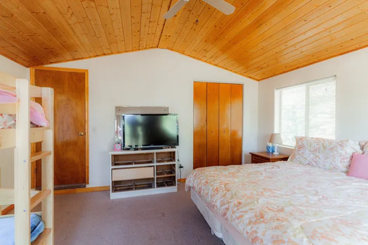 Bedroom with carpet floors, a closet, wood ceiling, and ceiling fan