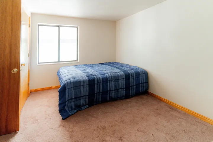 Bedroom featuring light carpet and baseboards