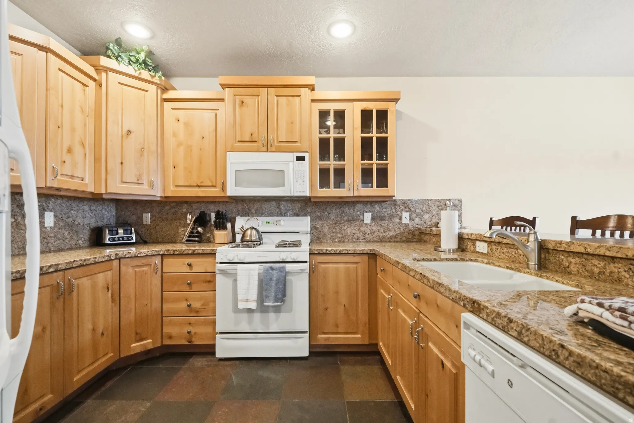 Kitchen featuring a breakfast bar area, stone tile flooring, solid wood cabinets