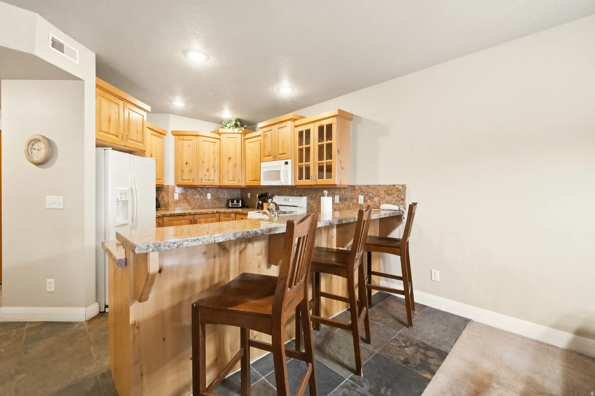 Kitchen featuring a breakfast bar area, stone tile flooring, solid wood cabinets