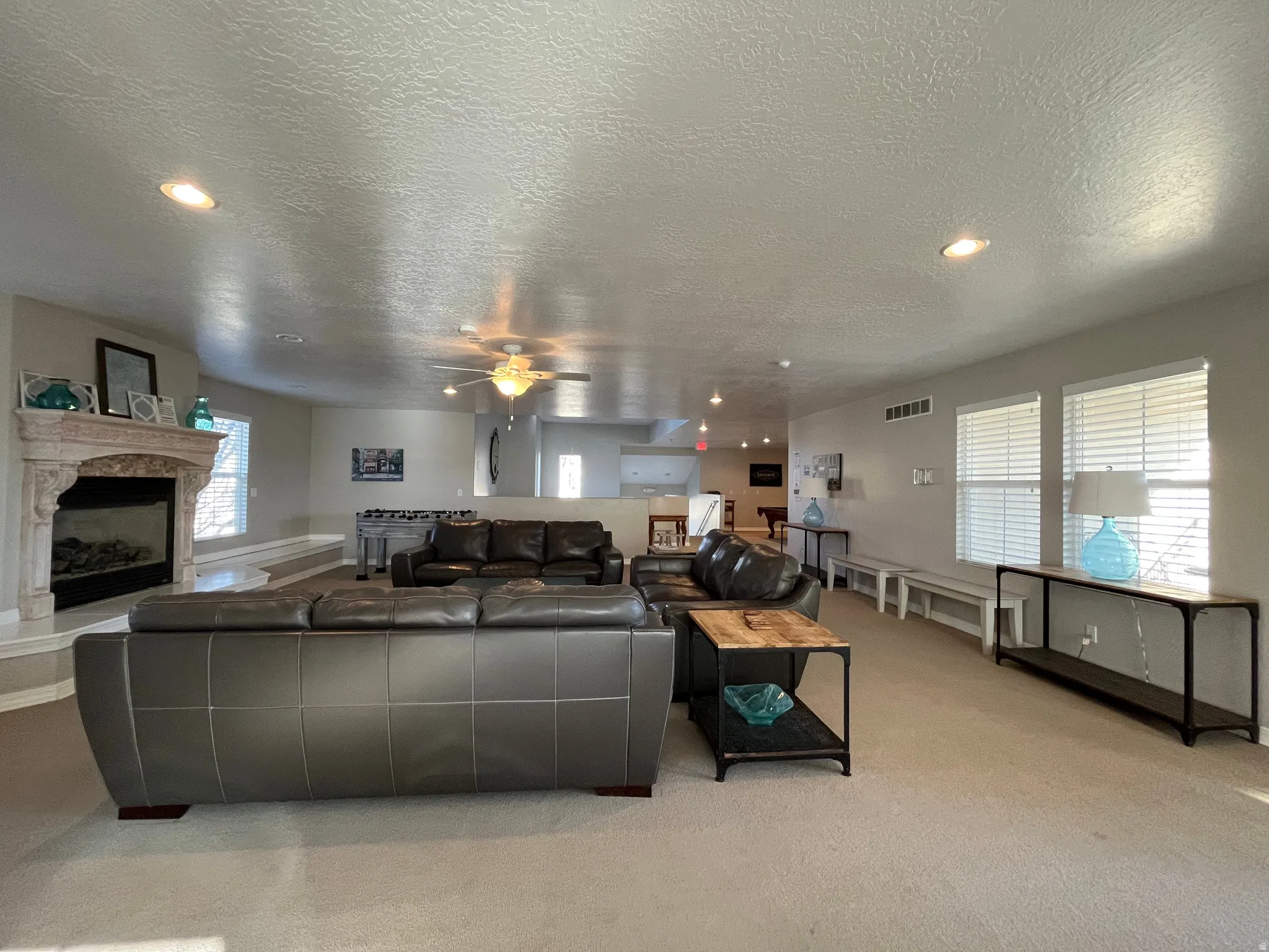 Clubhouse gathering room with a fireplace, a textured ceiling, recessed lighting, light carpet, and ceiling fan