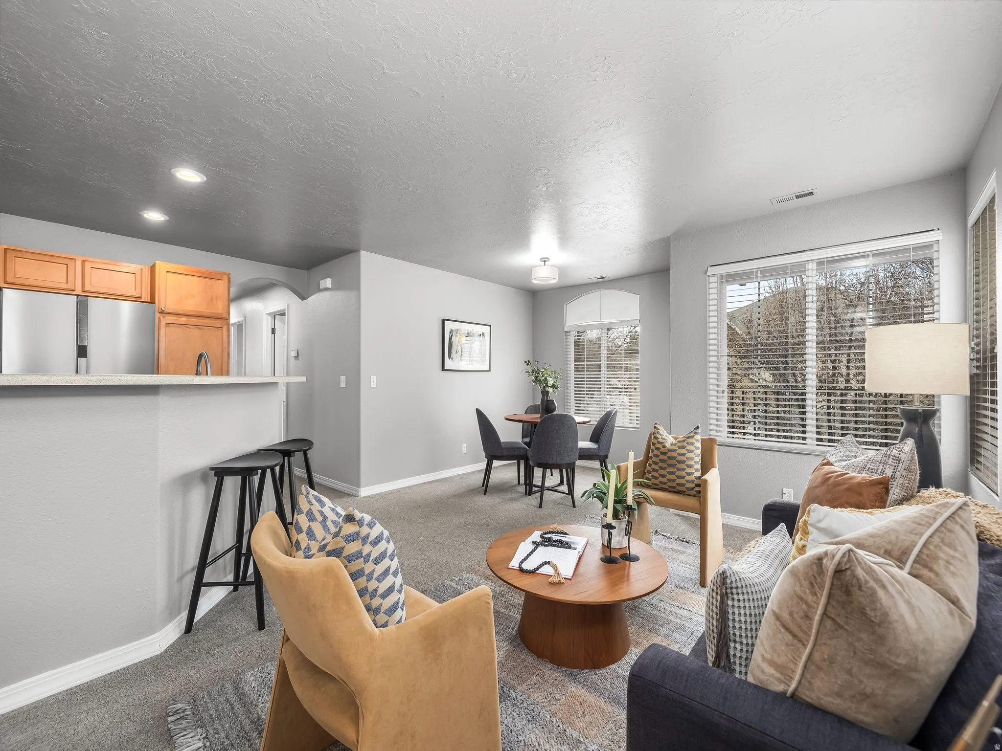 Living room featuring arched walkways, carpet flooring, a textured ceiling, and recessed lighting
