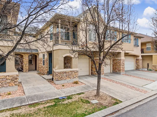 View of front of property featuring driveway, stone siding, a balcony, and an attached garage