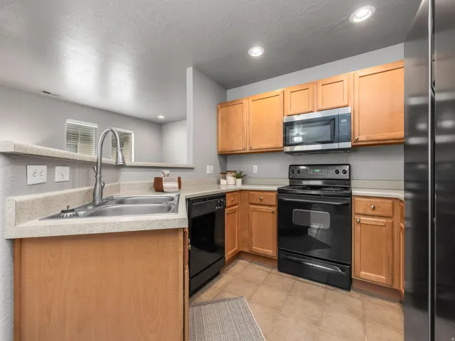 Kitchen with black appliances, light countertops, recessed lighting, a peninsula, and a textured ceiling
