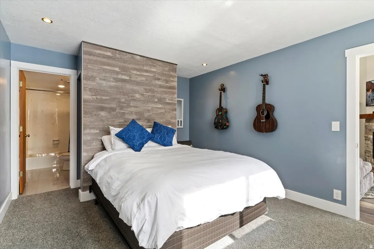 Carpeted bedroom with connected bathroom and baseboards