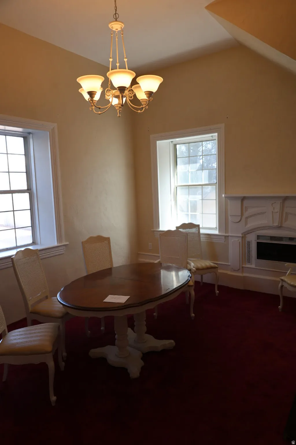 Dining area with suspended lighting, carpet, and a fireplace