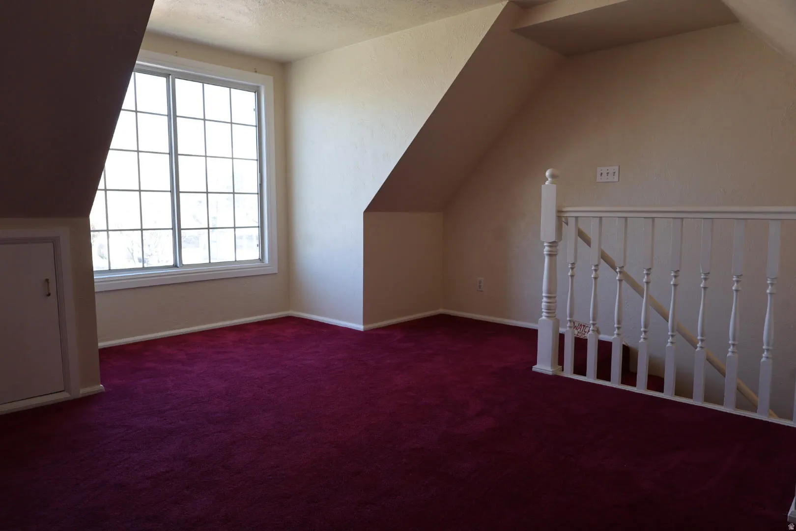 Bonus room with vaulted ceiling and dark colored carpet