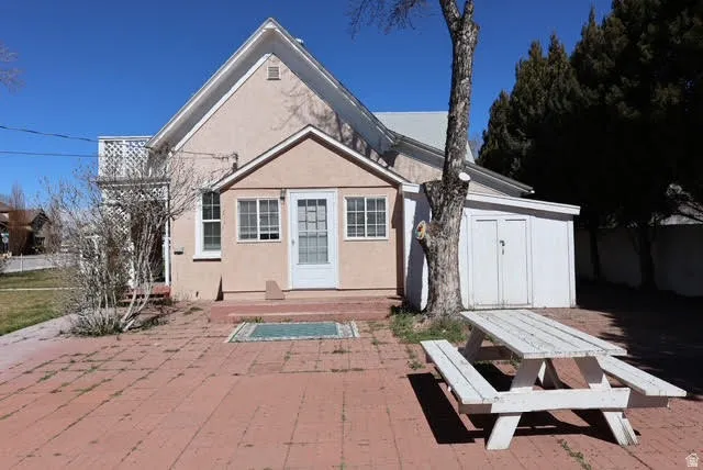 Back of house featuring stucco siding, a storage shed, and a wooden deck