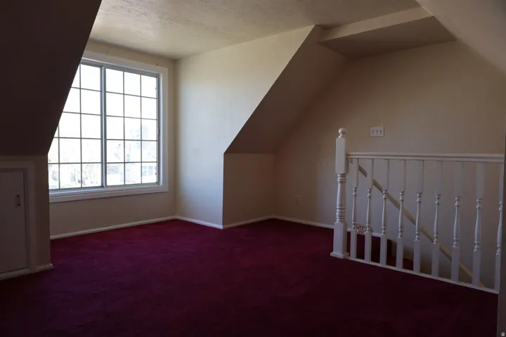 Additional living space featuring dark carpet and baseboards