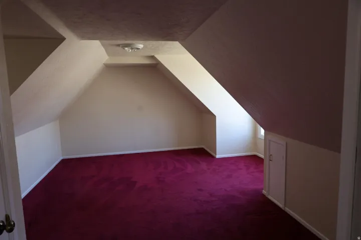Additional living space with dark carpet and baseboards