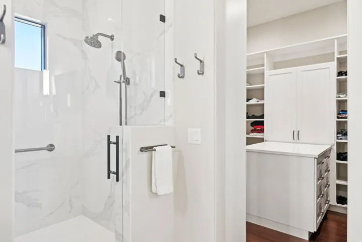 Full bath featuring a marble finish shower, dark wood-style floors, and a spacious closet