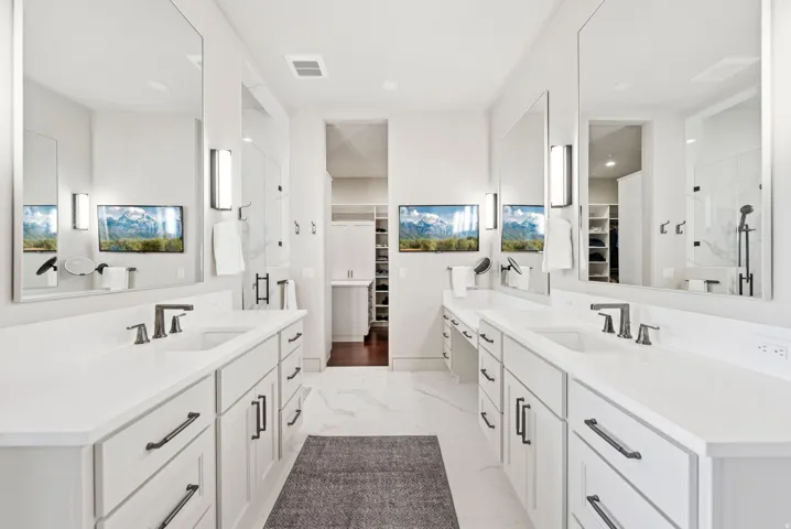 Bathroom with a walk in closet, two vanities, and a stall shower