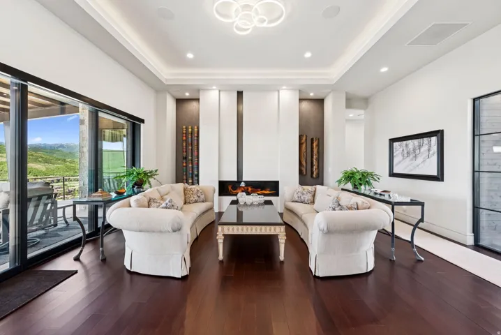 Living area featuring a glass covered fireplace, hardwood / wood-style floors, and a tray ceiling