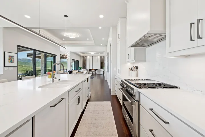 Kitchen with high end stainless steel range oven, white cabinets, a tray ceiling, dark wood-style floors, and light stone counters