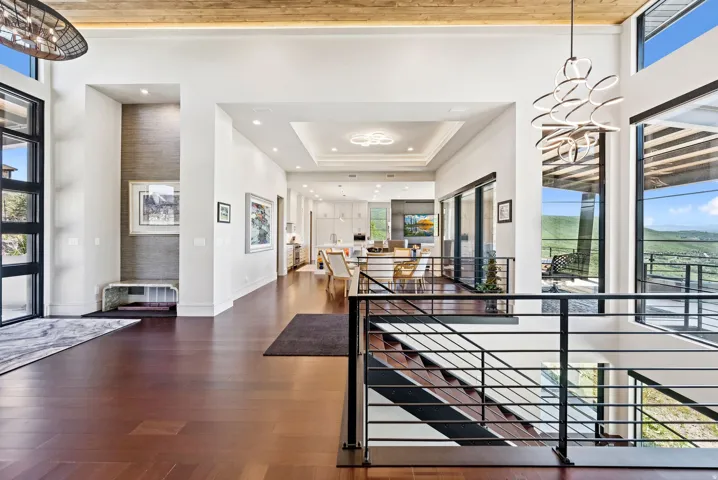 Foyer entrance with dark wood-type flooring, a tray ceiling, and suspended lighting