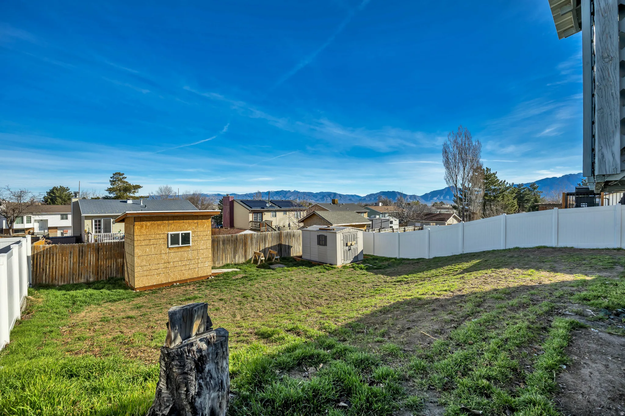 Fenced backyard with a storage unit, a residential view, and a mountain view