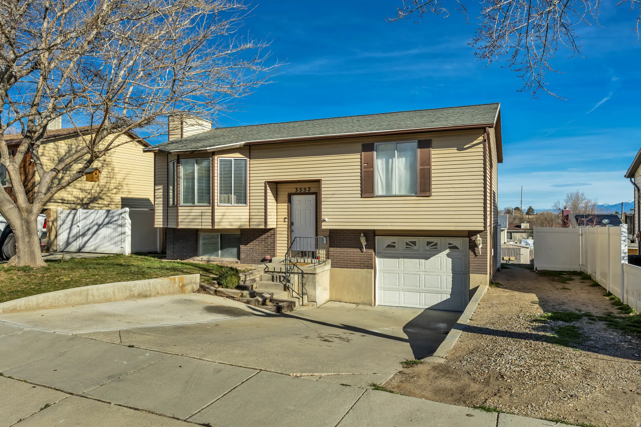 Split foyer home with brick siding, driveway, a garage, a chimney, and a shingled roof