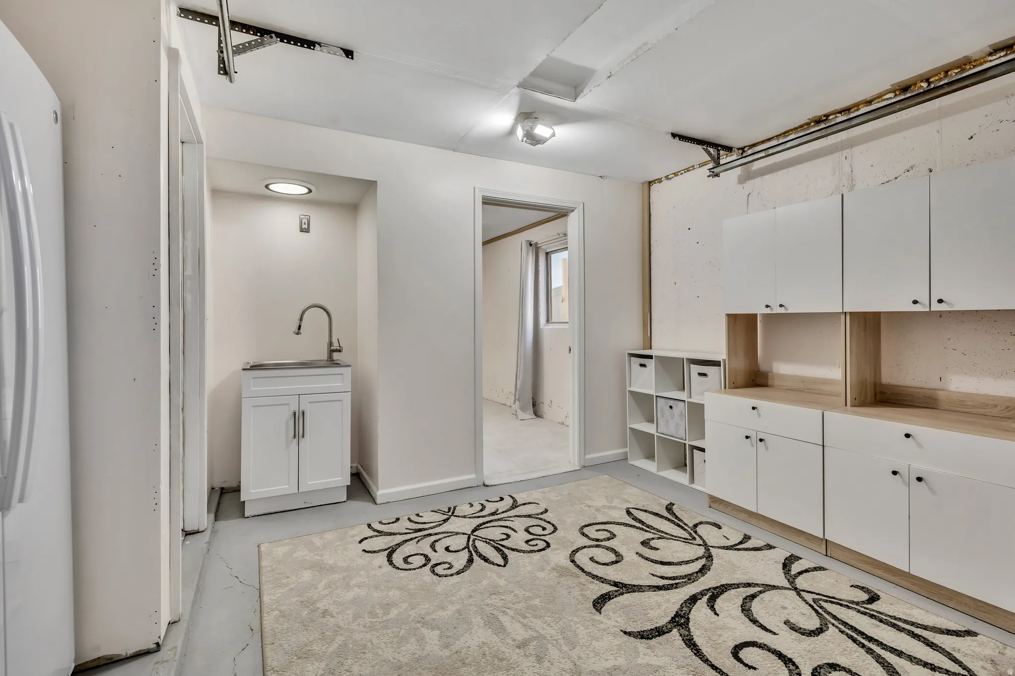 Laundry area with unfinished concrete flooring and a sink